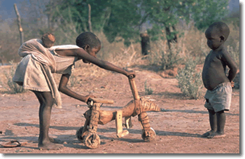 Zimbabwe: due bambini giocano con un artigianale e rudimentale triciclo di legno.